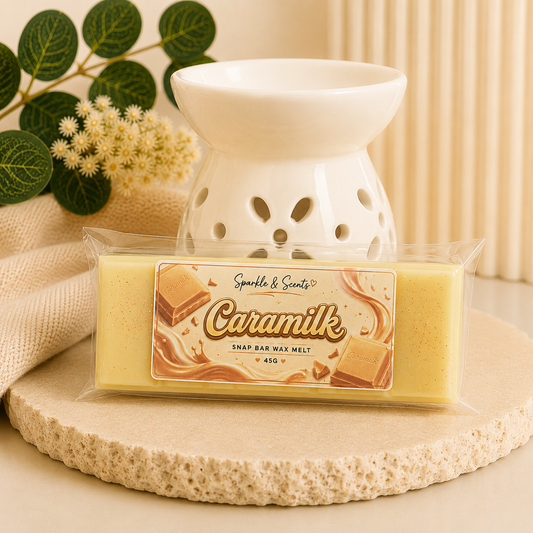 Caramilk wax melt package with a wax warmer on a decorative surface.
