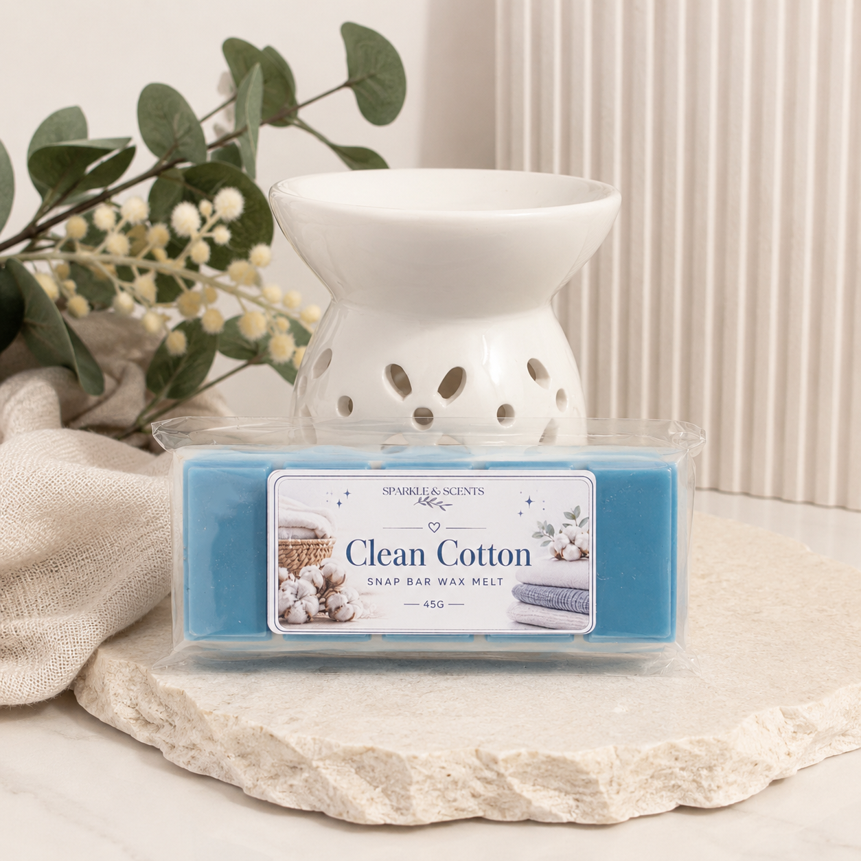 Clean Cotton wax melt with a white wax warmer on a stone surface with plants in the background