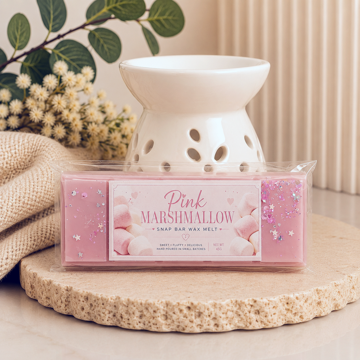 Pink Marshmallow wax melt packaging with a white wax warmer on a decorative surface.