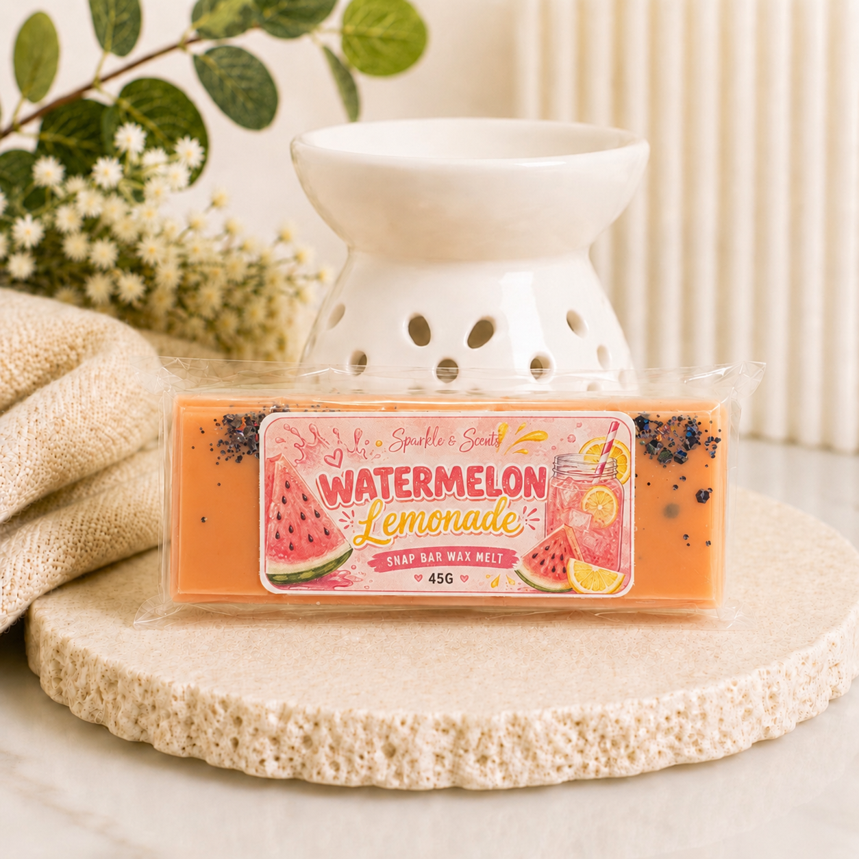 Watermelon Lemonade wax melt with a white ceramic warmer on a textured surface.